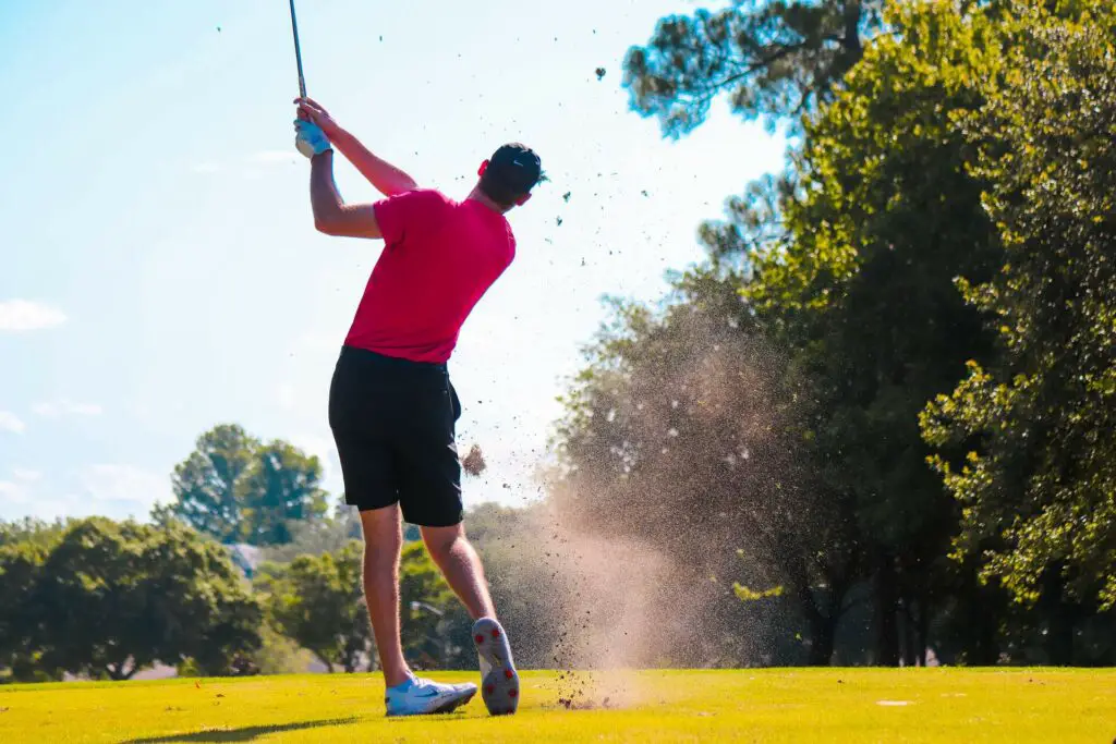 A man hitting a golf ball on the field