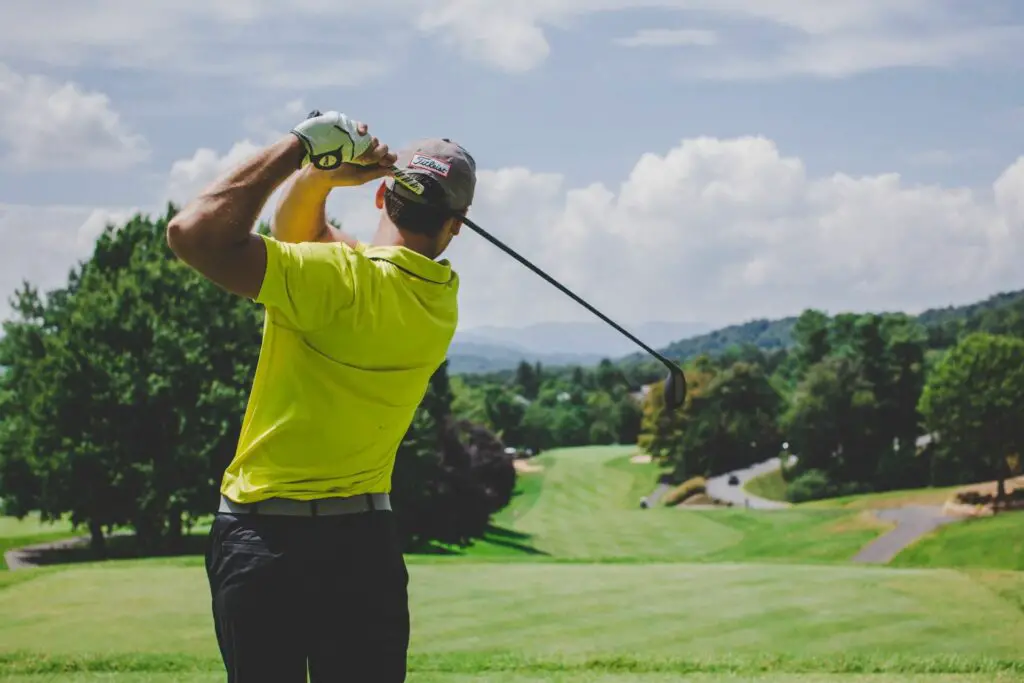 A man in a bright green shirt hit a ball with a club