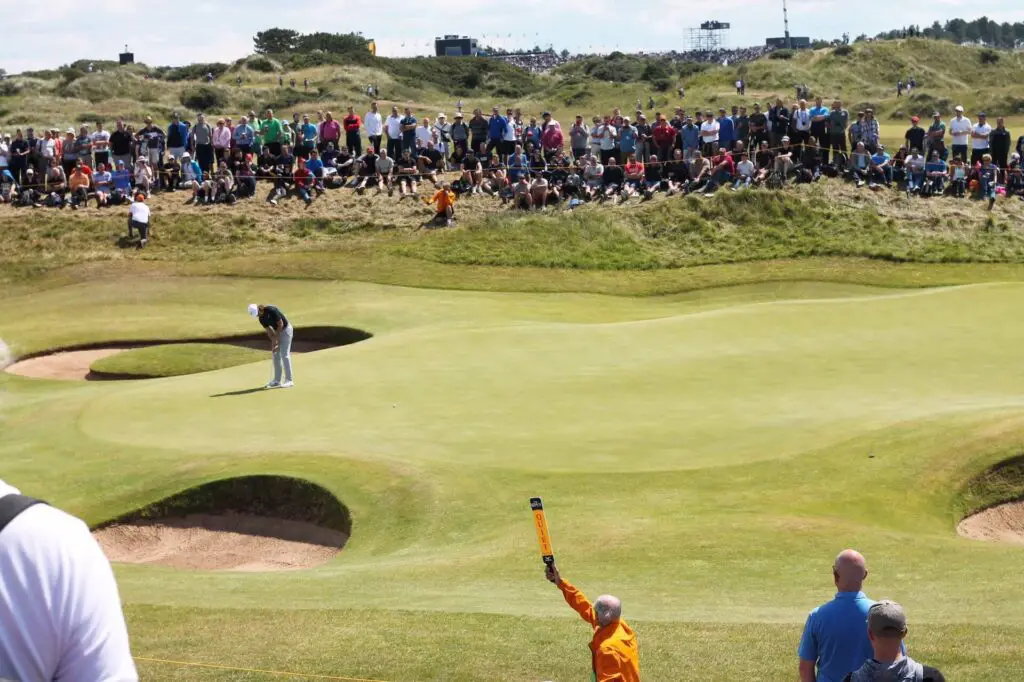 A depiction of a professional golf tournament with a crowd and a player in the middle