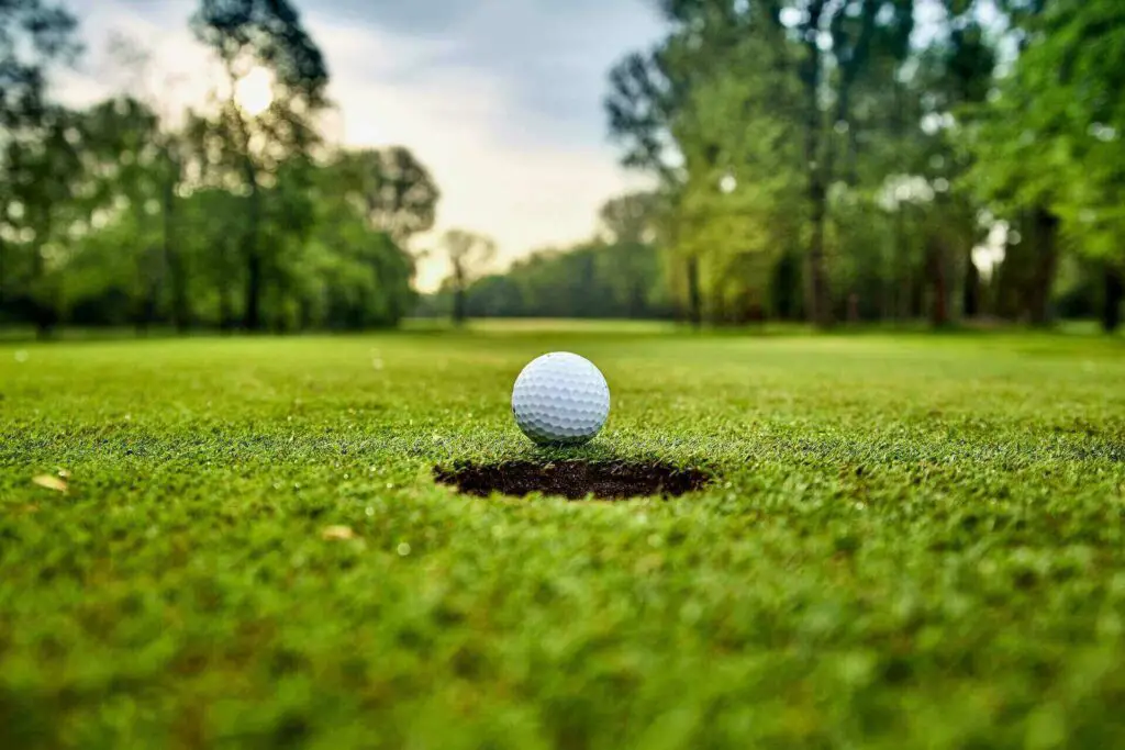 A golf ball standing close to a hole