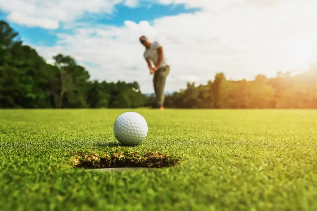 A golfer out of focus hitting the ball close to the hole