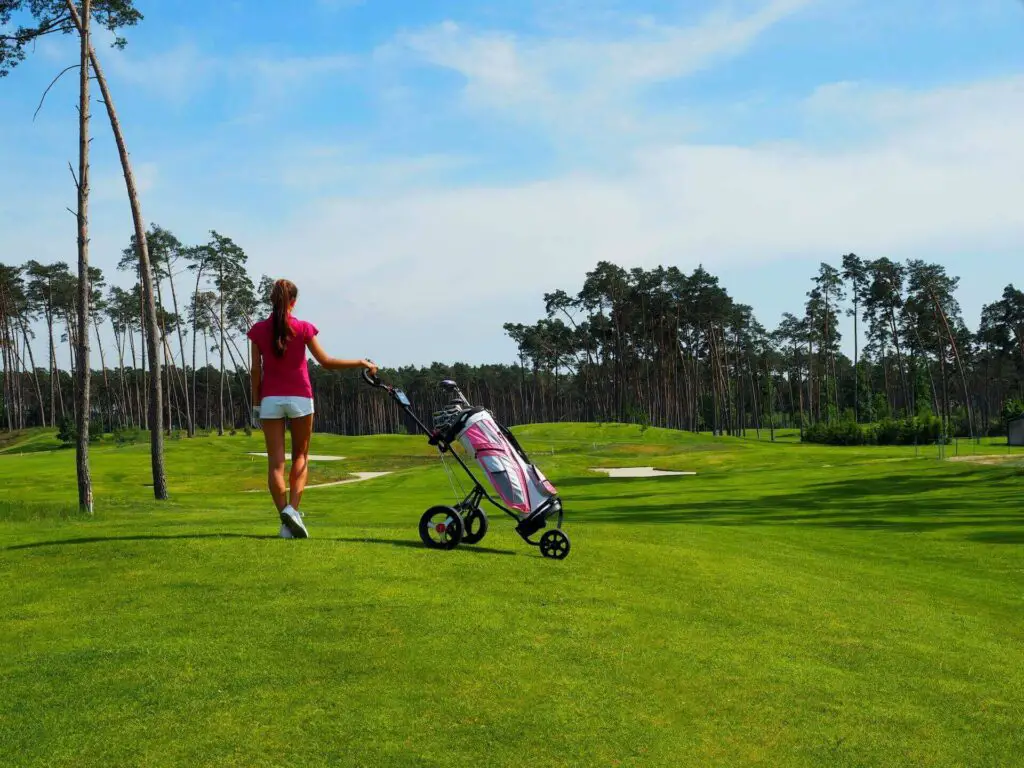  A girl holding the handle of a golf push cart