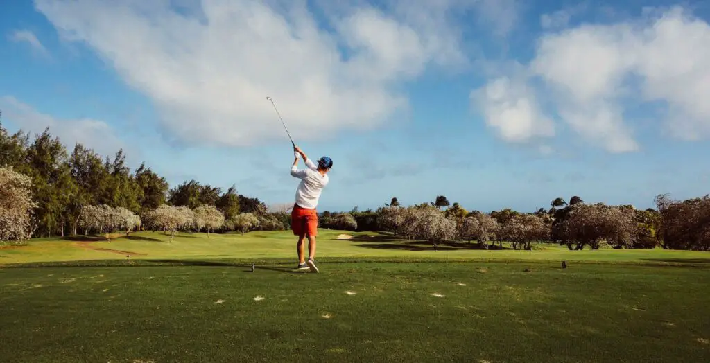 A man in a white shirt playing golf 