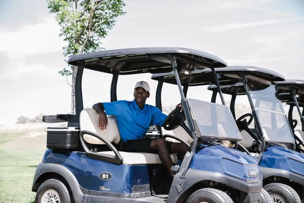 A man sitting in a golf cart next to other carts