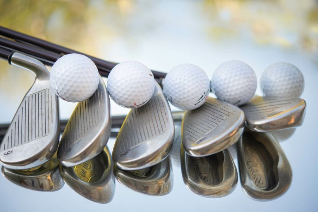 A row of golf clubs and balls on top of them.