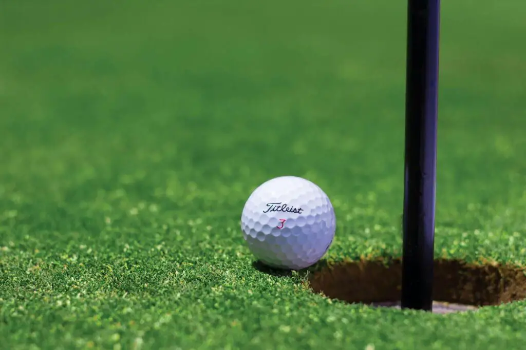 A golf ball near a golf hole 