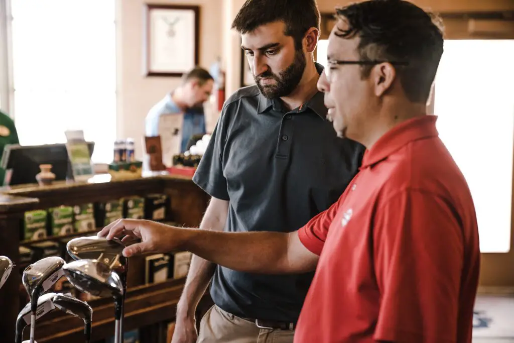 Two men standing next to golf clubs