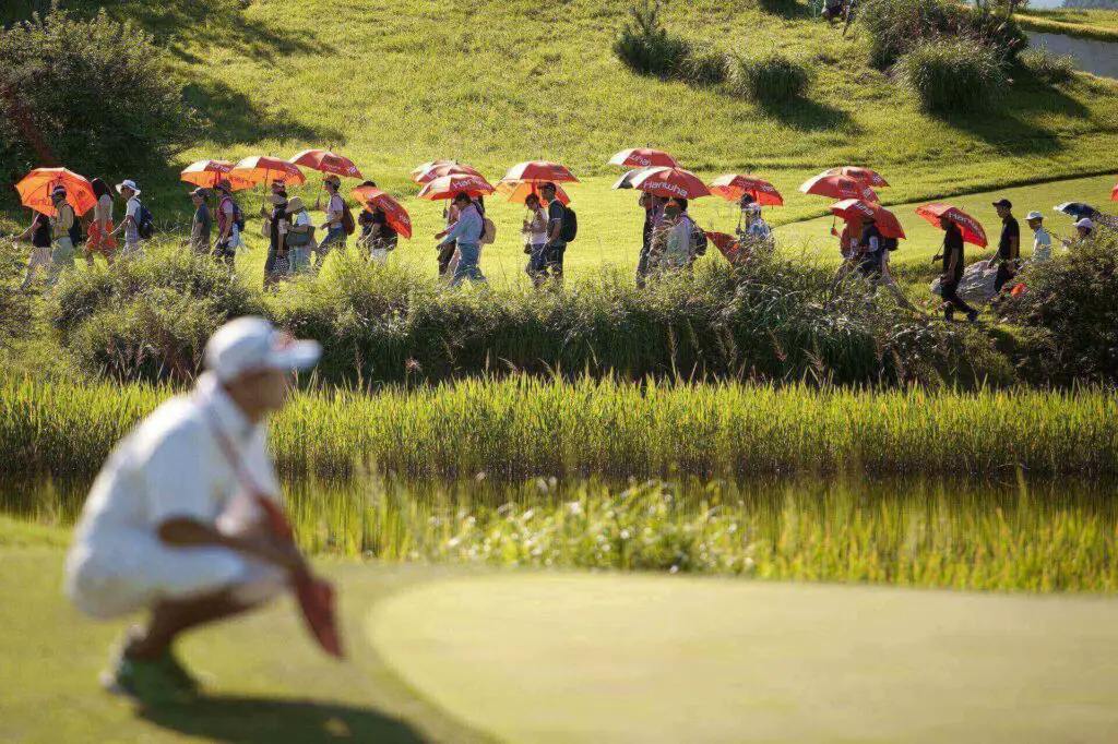A golfer squatting with spectators behind him