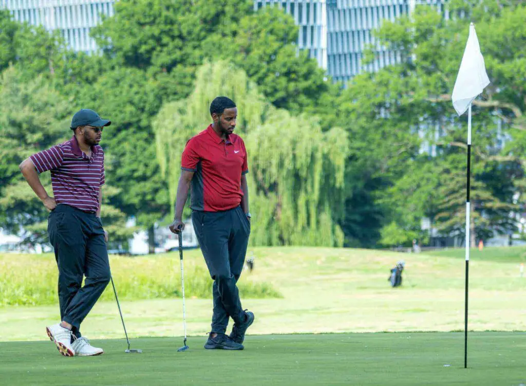 Two golfers standing next to a hole