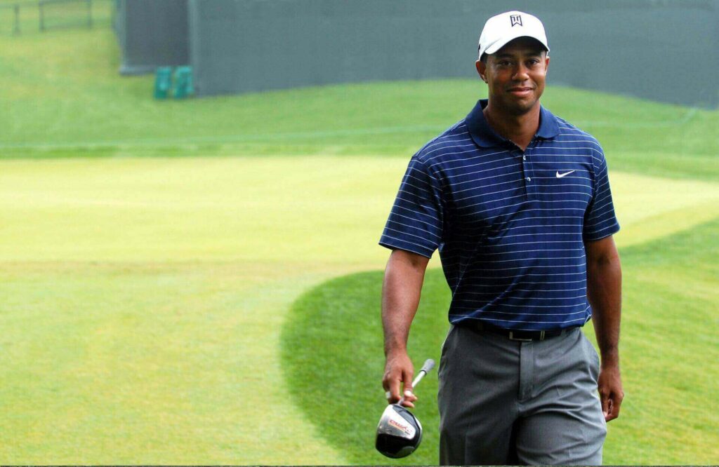 Tiger Woods smiling and carrying a wedge