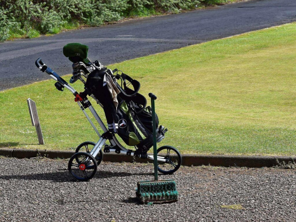 A golf push cart with a bag on it