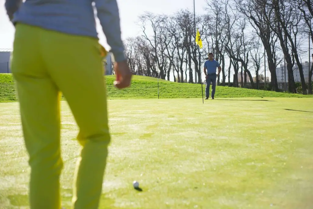 Two men playing golf near a hole