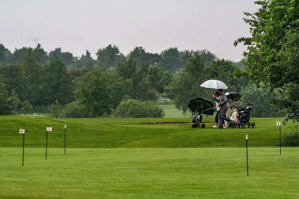 People on a golf course holding umbrellas