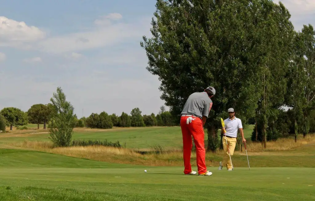 A man playing golf and another man watching him