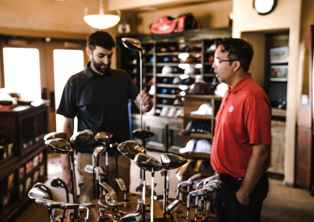 A man helping a golfer choose golf clubs
