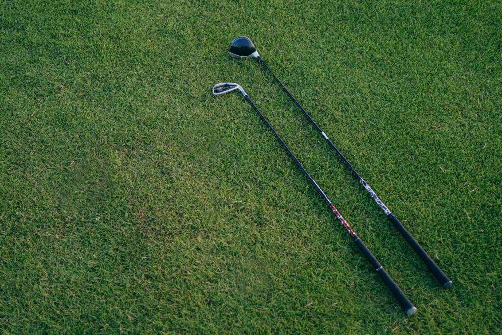 Two black golf clubs on the grass
