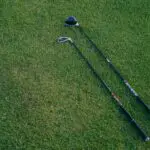 Two black golf clubs on the grass