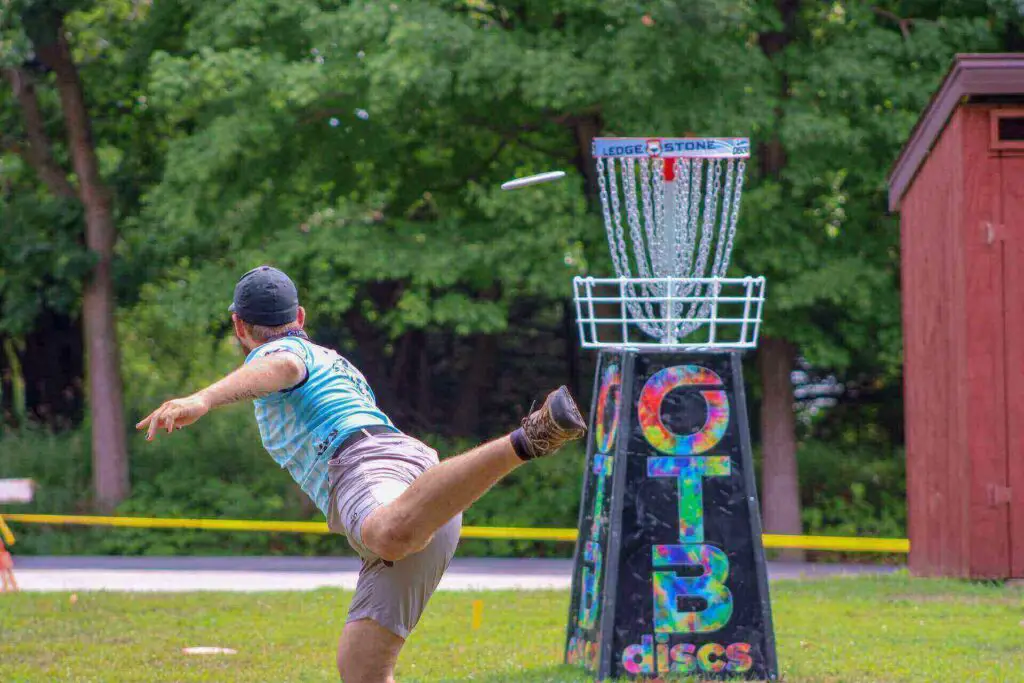 A man throwing a disc into a target basket
