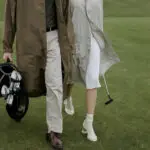 A couple walking and carrying a golf bag