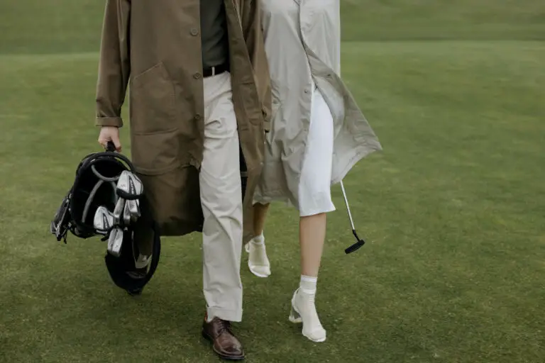 A couple walking and carrying a golf bag