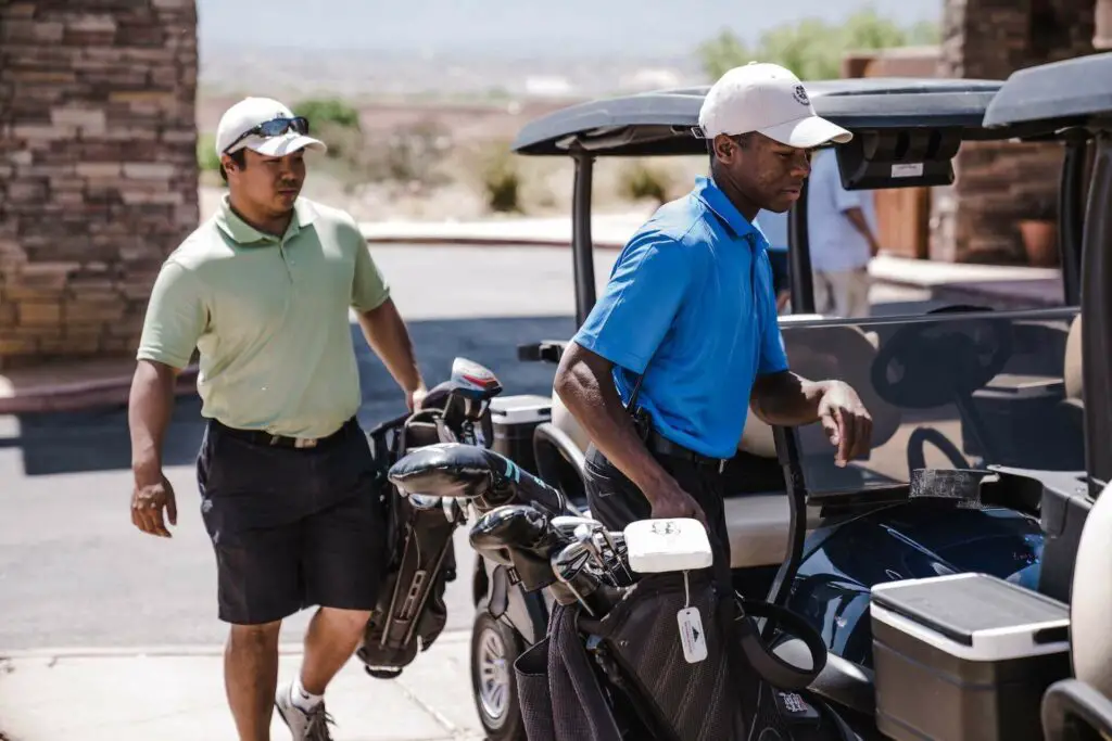 Two golfers with golf bags near carts