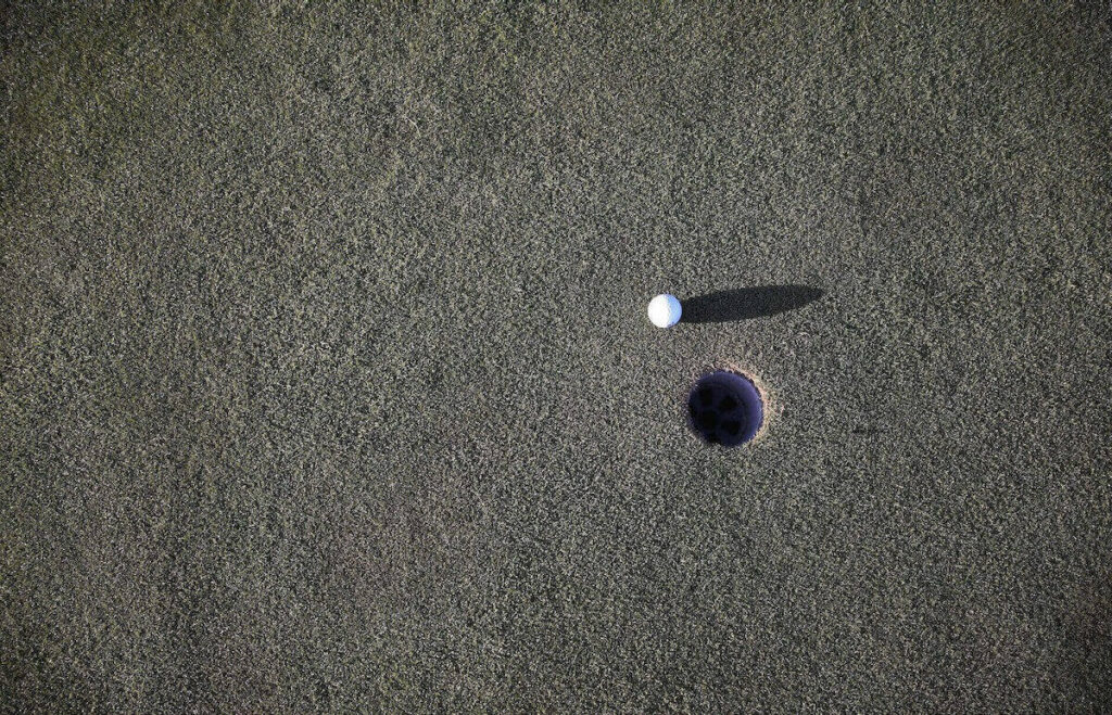 A golfing ball near a hole
