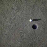 A golfing ball near a hole