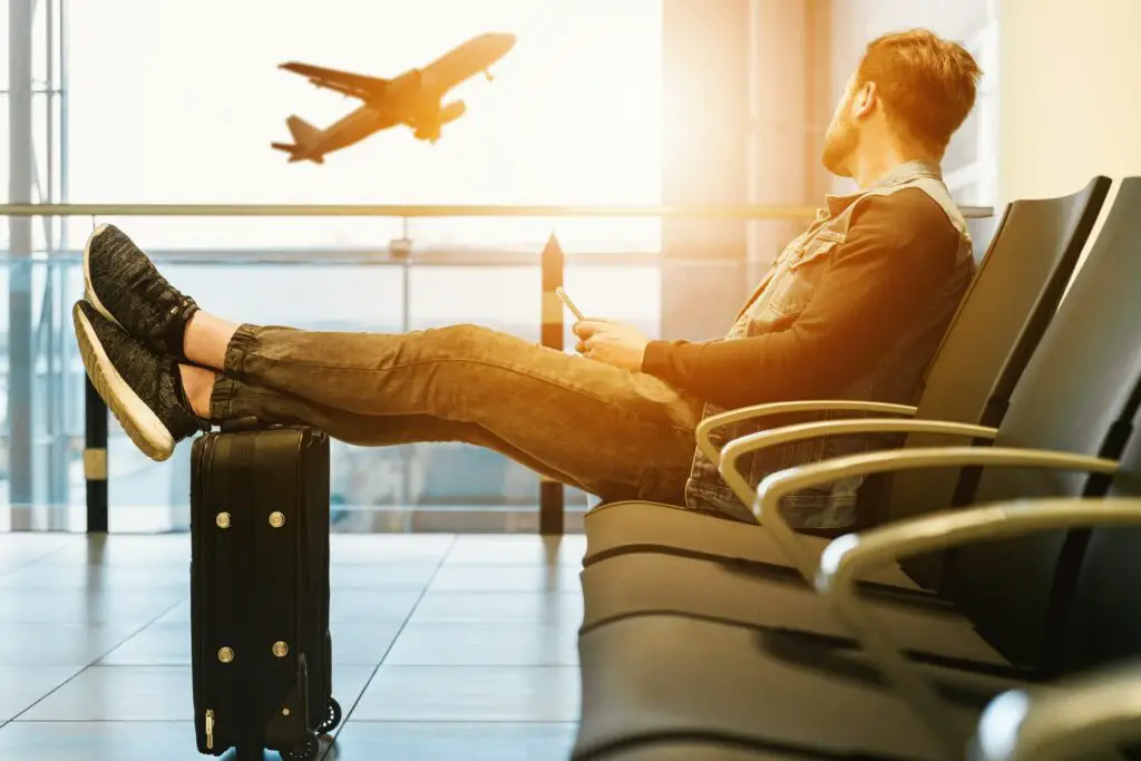 A man looking at a plane with his feet up on a bag