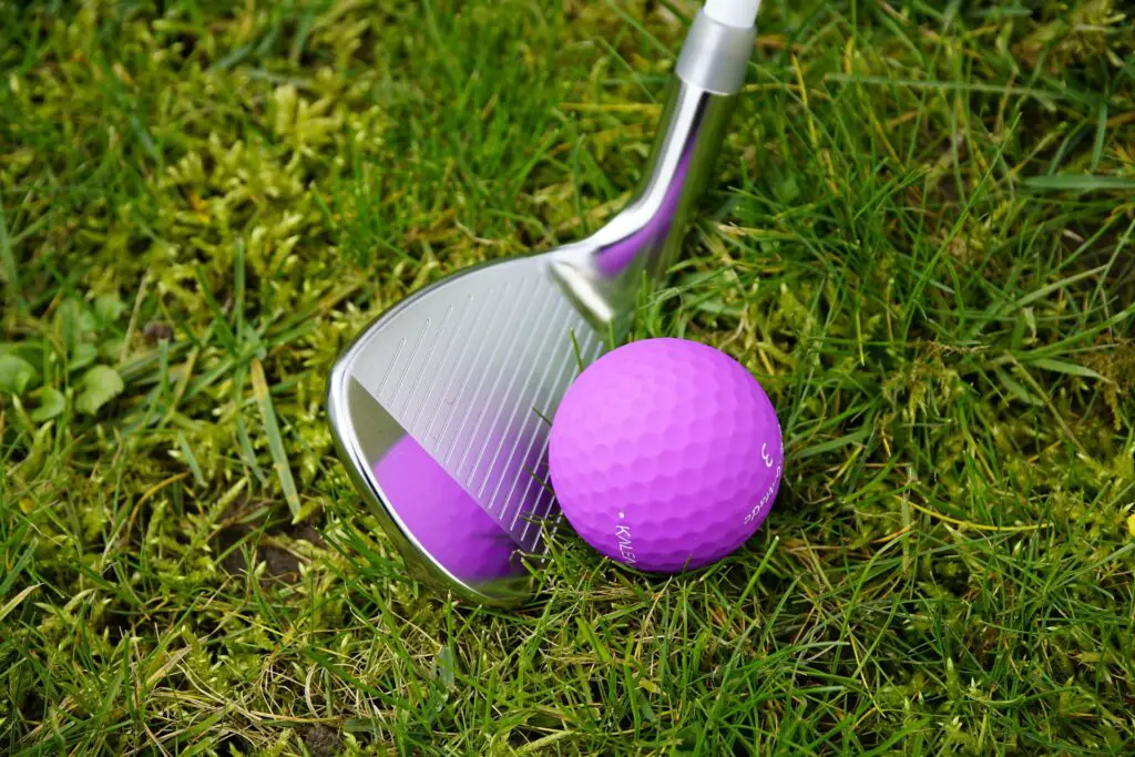 A wedge hitting a pink golf ball