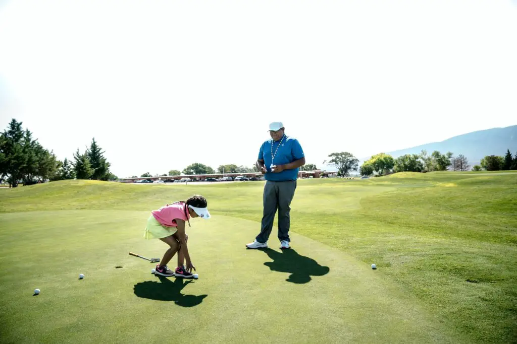 Man teaching a girl to play golf
