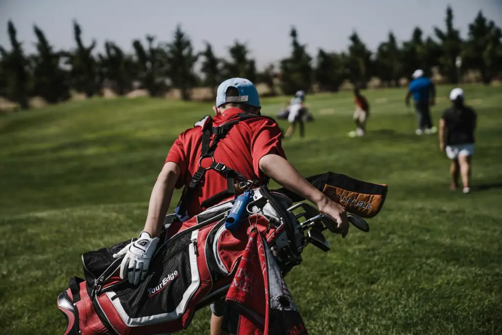 Man carrying a black and red golf bag
