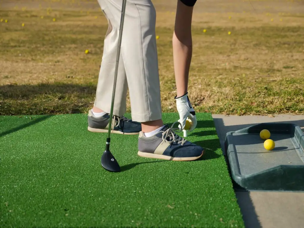 A golfer putting a ball on a tee and holding a club