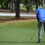 man in blue polo shirt and gray pants playing golf during daytime
